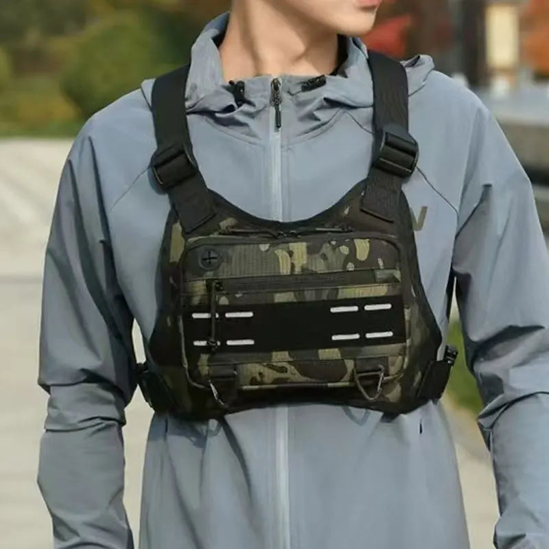 Mann in hellblauer Kapuzenjacke mit taktischem Brustgurt und Rucksack.