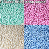 A close-up of colorful plastic beads or pellets in various shades of green, pink, and blue.