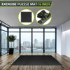 A black exercise puzzle mat is shown with measurements, placed on a wooden floor in a modern room.