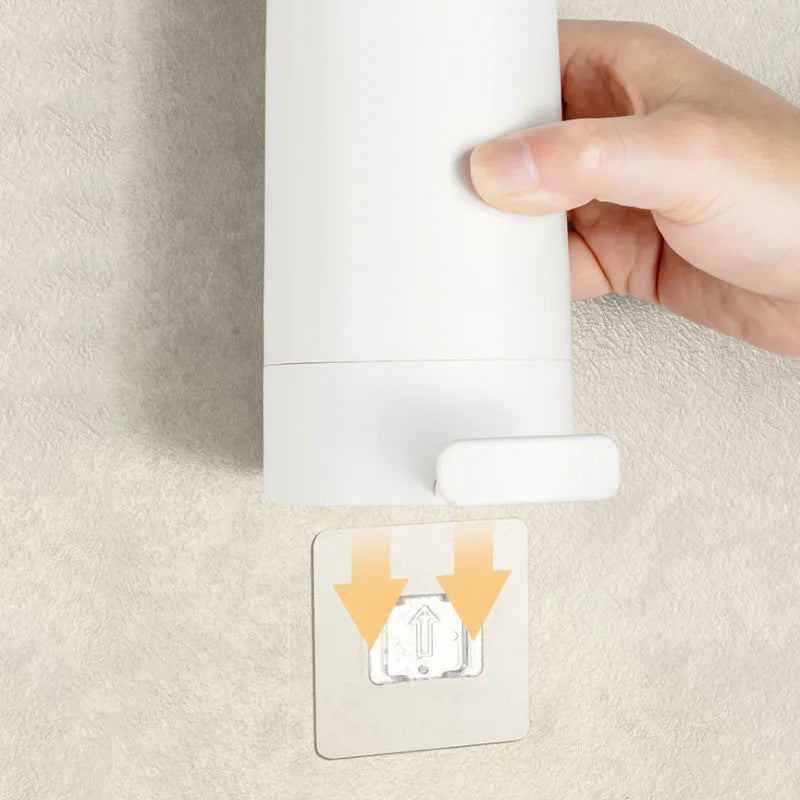 A hand is installing a white soap bar grinder and dispenser onto a wall mount.