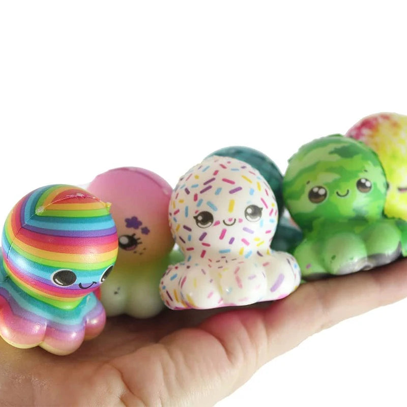 Une main tient plusieurs balles anti-stress de Noël colorées dans différentes nuances de vert, rose et jaune.