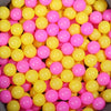 A close-up view of a large quantity of colorful plastic ball pit balls in shades of yellow and pink.
