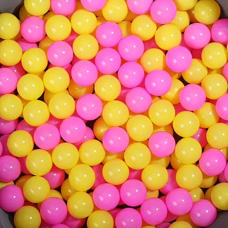 A close-up view of a large quantity of colorful plastic ball pit balls in shades of yellow and pink.