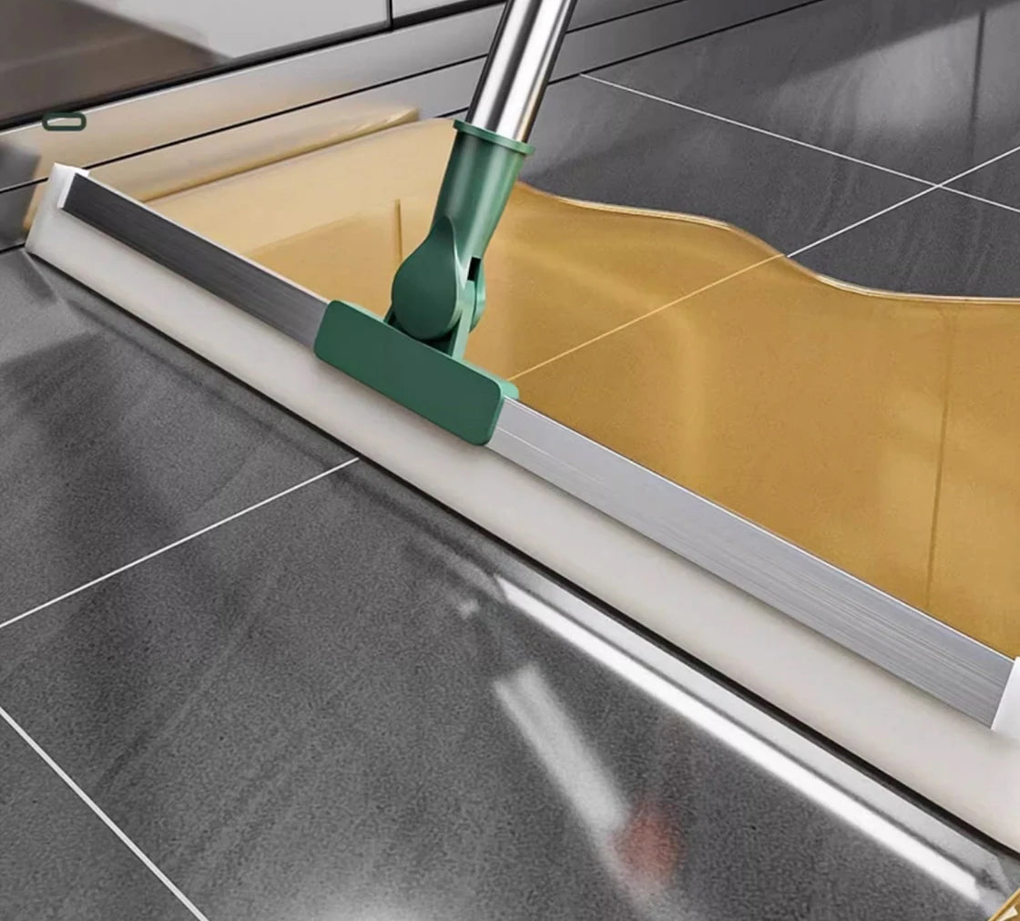 A silicone scraper broom and squeegee is shown cleaning a glass surface with a yellow cleaning cloth.