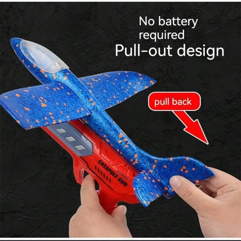 A hand is pulling back a red and blue foam catapult glider plane with a pull-out design.