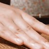 A hand rests on a woven mat, showing the texture and surface of a foldable double-sided cooling mat.
