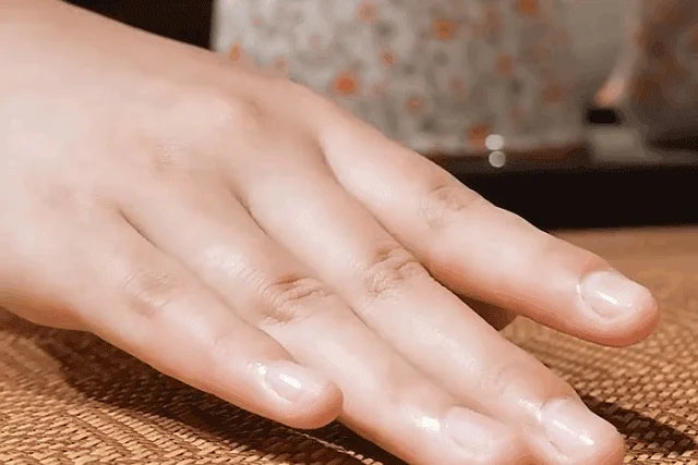 A hand rests on a woven mat, showing the texture and surface of a foldable double-sided cooling mat.