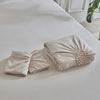 A set of three-dimensional pleated floral duvet covers in a soft beige color displayed on a white bed.