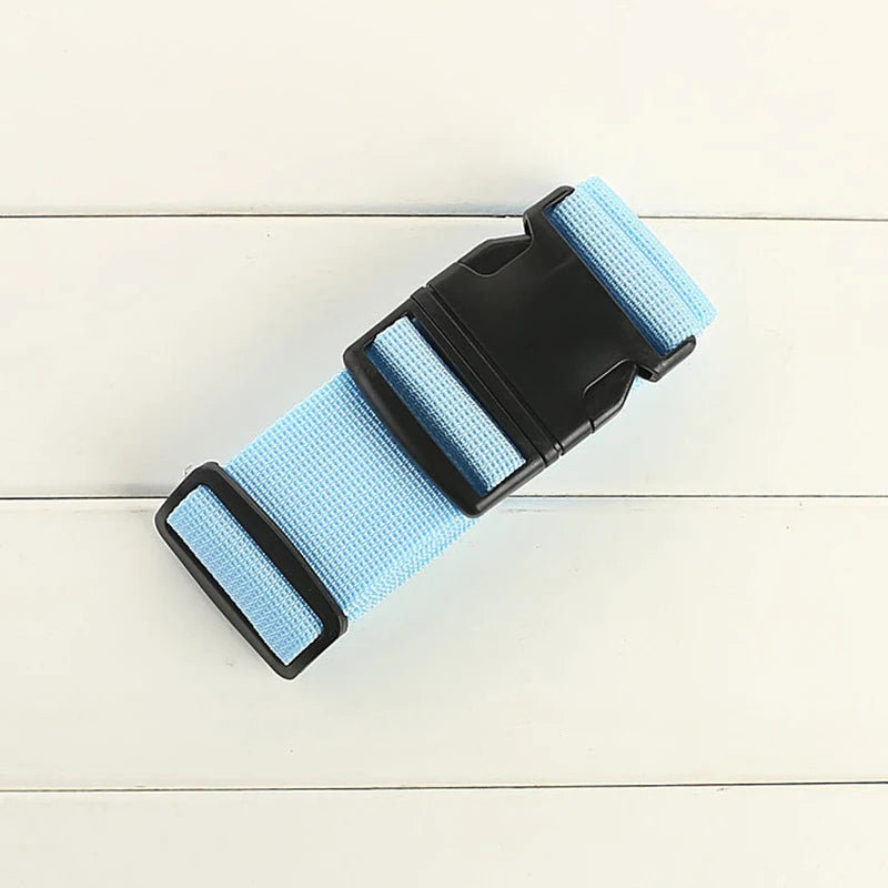 A light blue adjustable polyester luggage strap with a black buckle is shown on a white wooden surface.