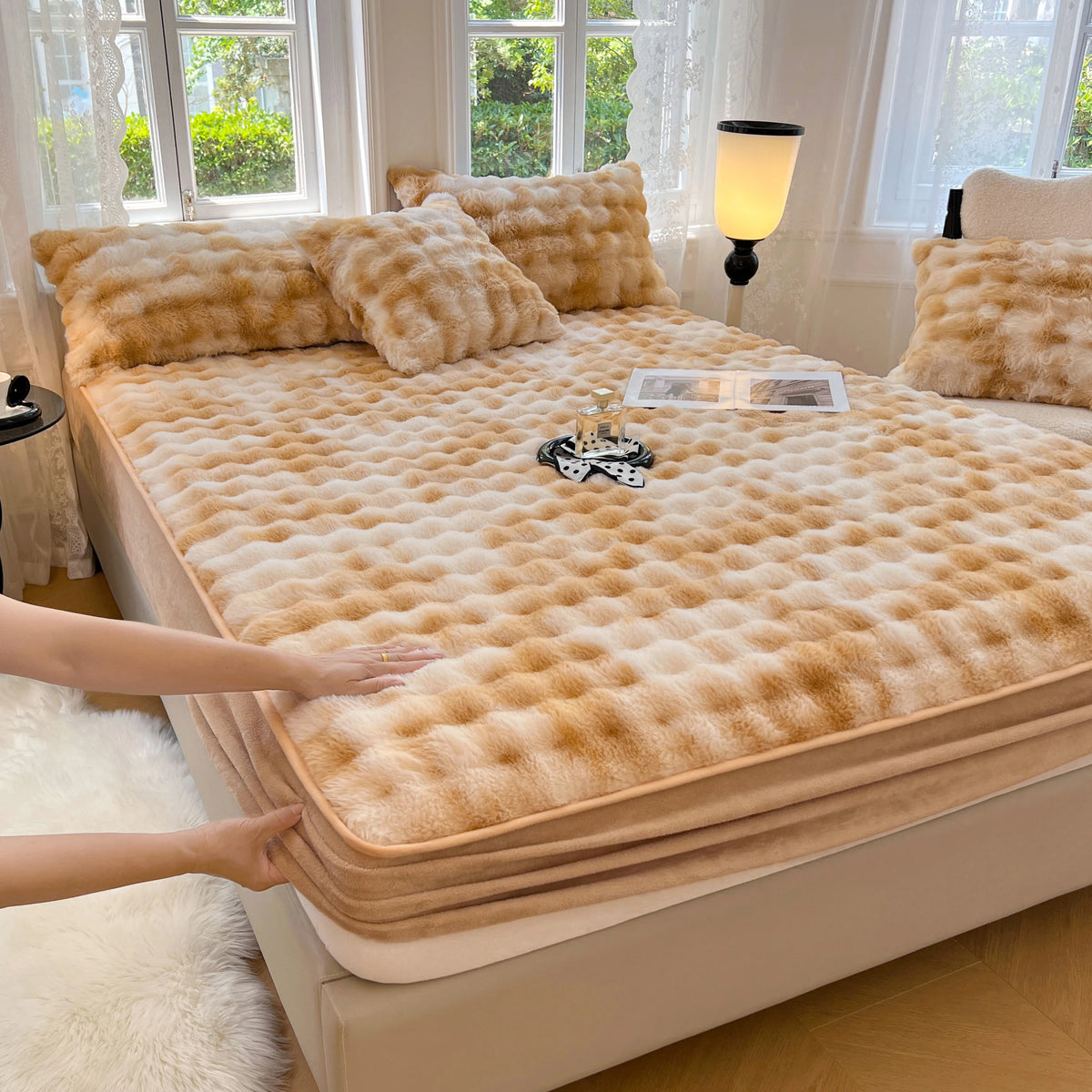 A tan luxury faux fur fitted sheet and pillowcase set displayed on a bed with natural light.