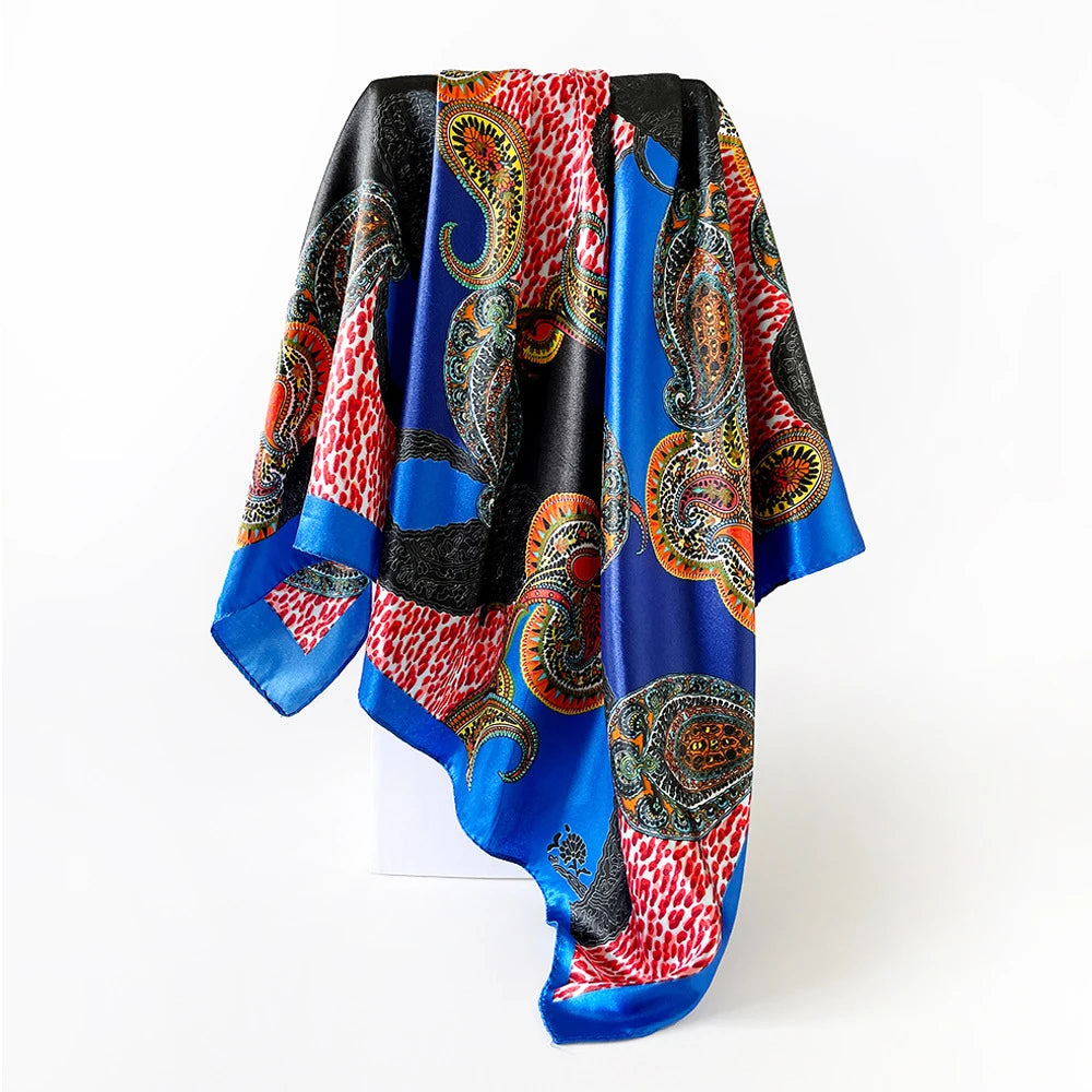 A vibrant blue and red leopard paisley square scarf draped on a white surface.