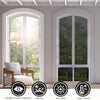 A white arched window with a privacy film installed, showing a view of trees and greenery.