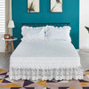 White ruffled lace bed skirt with elastic fit on a bed in a teal room.