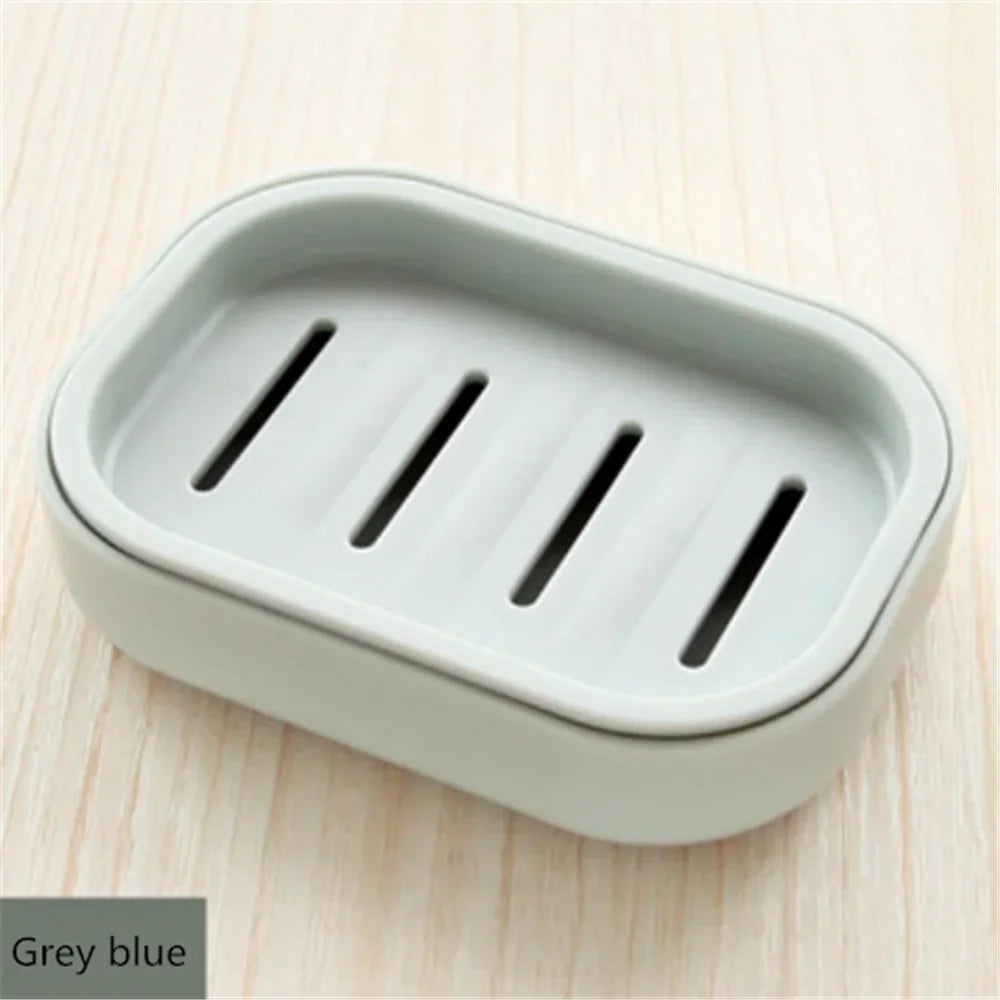 A grey blue compact travel soap holder with a secure lid is shown on a light wooden surface.