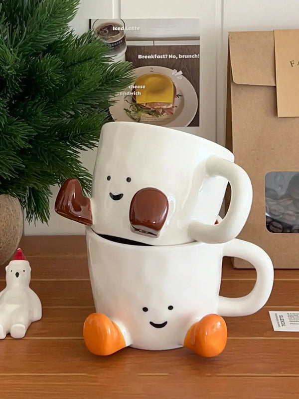 Tasse à café en céramique blanche en forme de visage souriant avec des accents marron, posée sur une surface en bois.