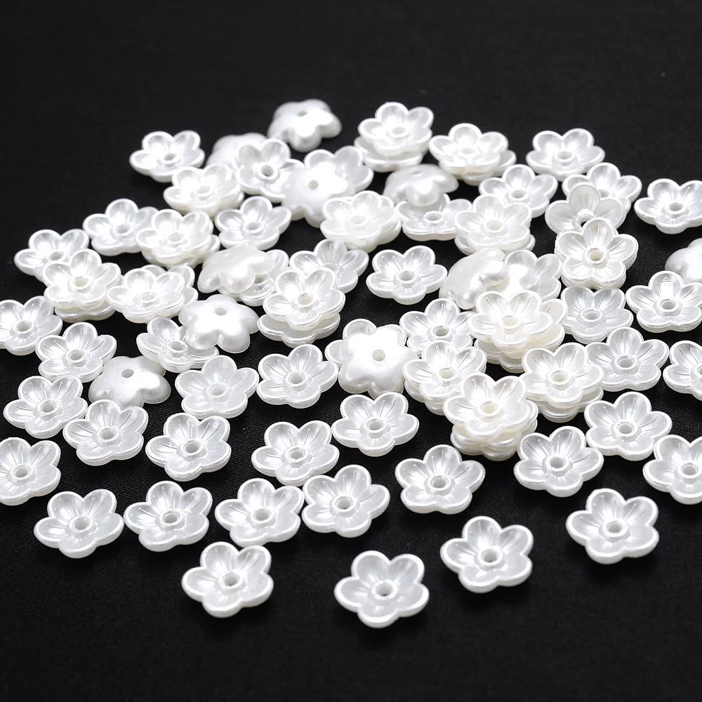A pile of 100 white acrylic pearl spacer beads for jewelry making.