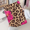 A leopard print tablet case featuring pink floral accents, shown on a white surface.