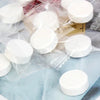 Packaged white portable compressed cleansing towels in clear plastic bags