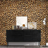 A dark dresser with decorative items set against a leopard print wallpaper background.