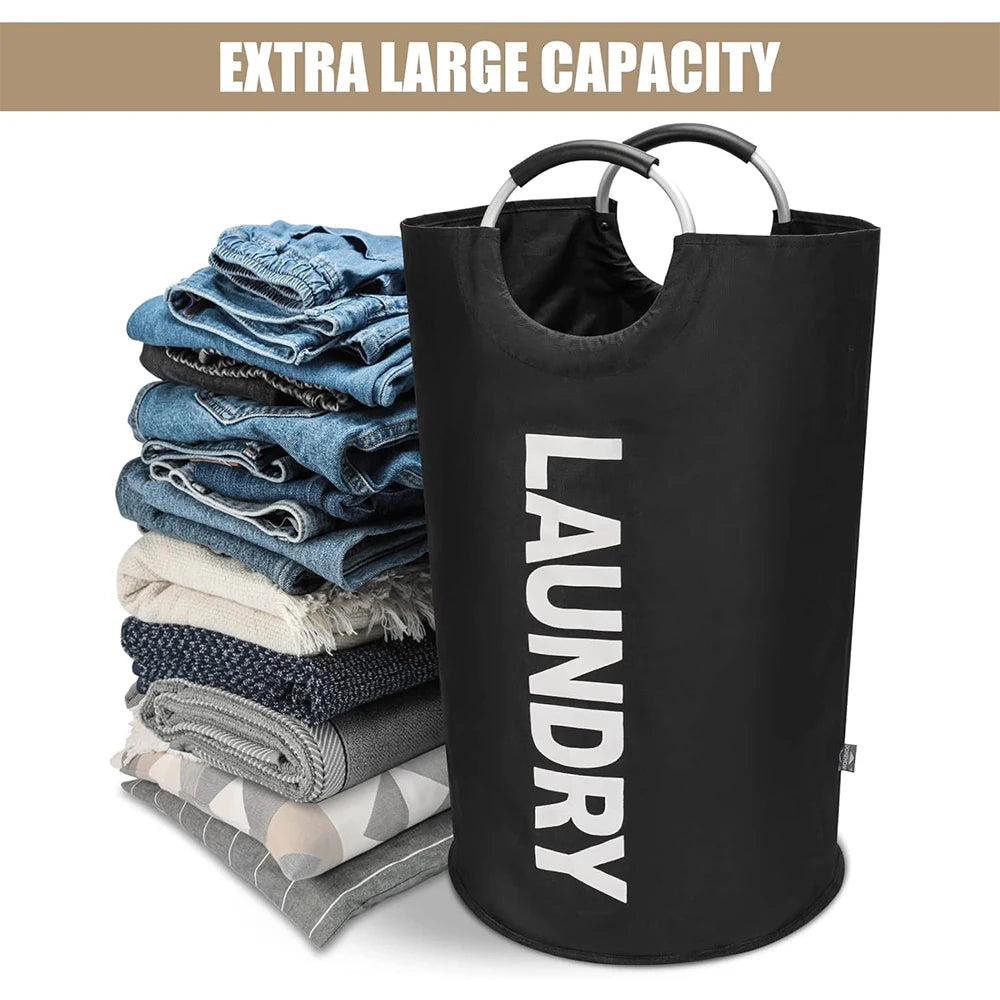 A black collapsible laundry basket with a handle is shown next to a stack of blue and gray clothes.