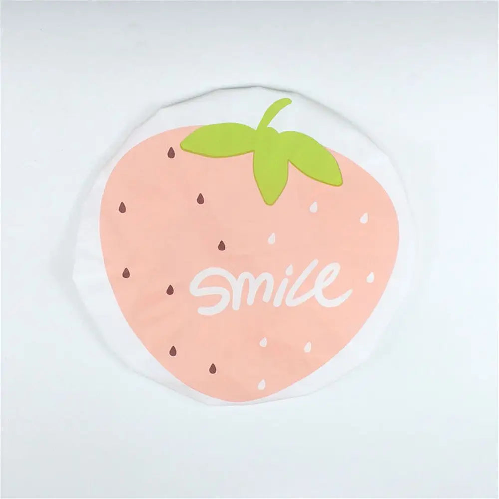 A pink strawberry design with a green leaf and the word smile on a clear waterproof shower cap.