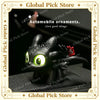 A black Toothless car ornament with glowing green eyes and movable wings displayed on a dark surface.