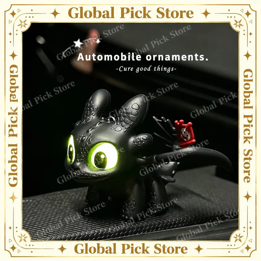 A black Toothless car ornament with glowing green eyes and movable wings displayed on a dark surface.