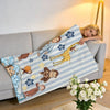 A striped blanket featuring cartoon animals and flowers draped over a gray sofa.