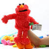 A bright red Elmo hand puppet made of soft plush toy material being held by a person.