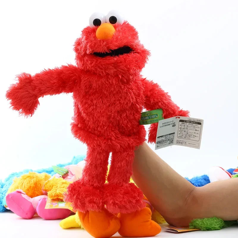A bright red Elmo hand puppet made of soft plush toy material being held by a person.