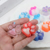 A hand holds various squishy cat paw fidget toys in pink, orange, and blue colors.