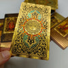 A gold foil tarot card featuring a sun design and intricate decorative borders, held by a hand.