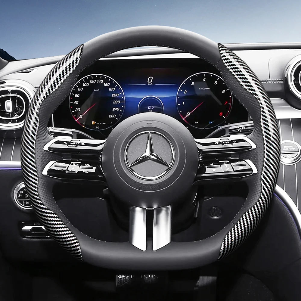 Close-up view of a black steering wheel with carbon fiber texture covers and digital instrument cluster in a Mercedes-Benz in