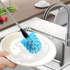 A hand is using a blue sponge brush on a white plate under a kitchen faucet for cleaning.