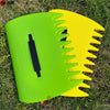 A pair of bright green and yellow ergonomic leaf grabber rake tools lying on green grass.