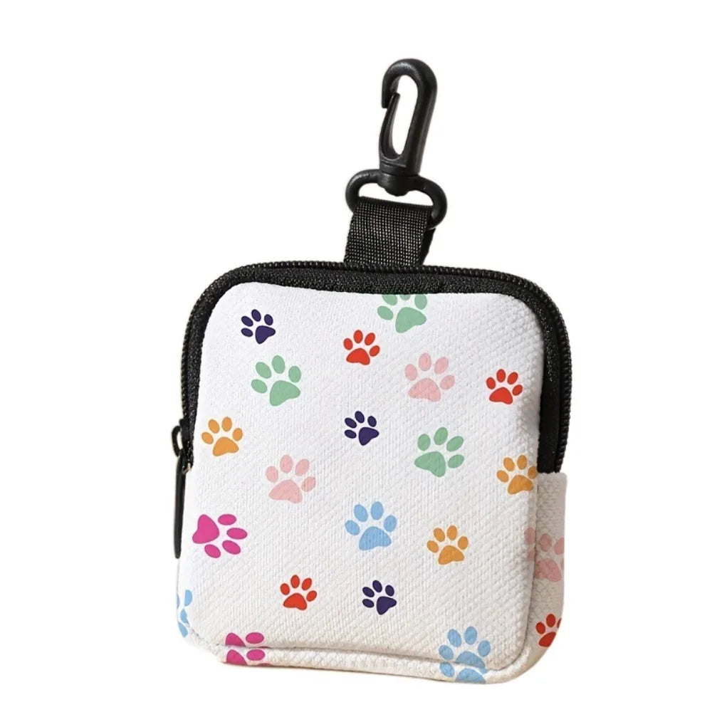A small white coin purse with a black strap featuring a colorful pattern of paw prints.