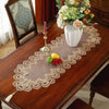 A brown wooden table is decorated with a sheer lace runner and fruit, set in a traditional interior.