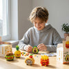 A boy is assembling a set of cute micro building blocks figurines on a wooden table.