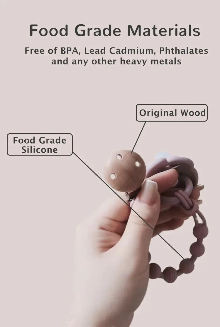A hand is holding a silicone pacifier clip with a teether made from original wood.