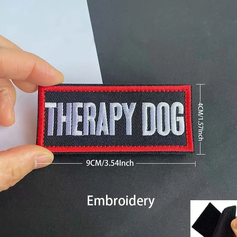 A black embroidered patch with red and white text Therapy Dog on a dark background.