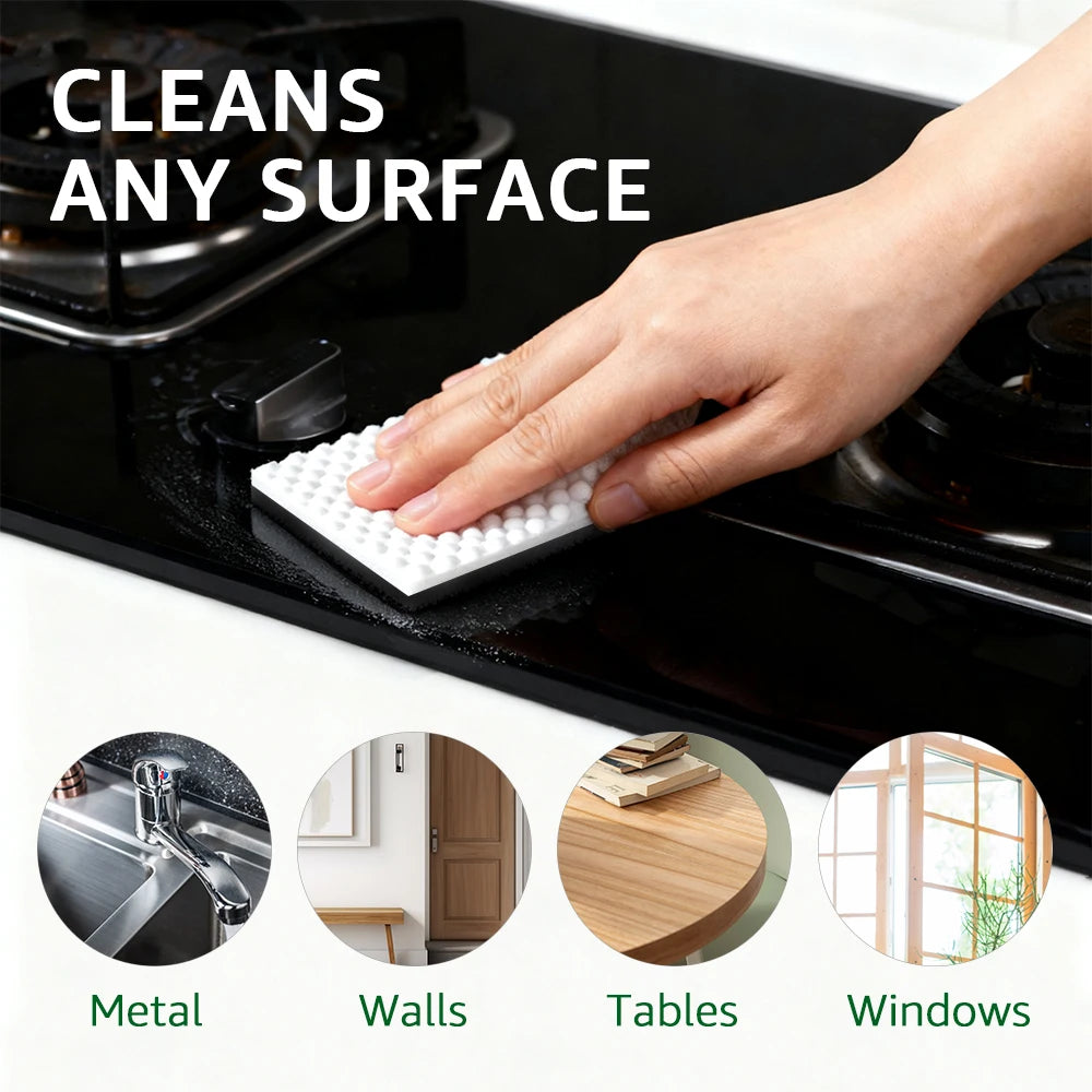A hand uses a white magic eraser sponge to clean a black stovetop surface.