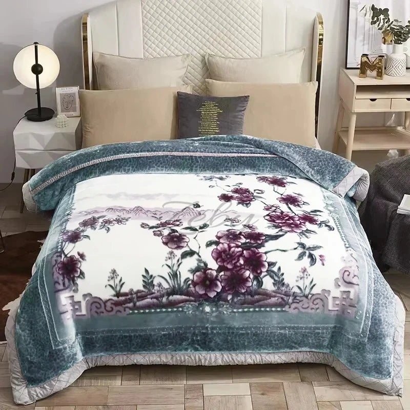 A weighted plush raschel blanket in teal and white floral pattern displayed on a bed.