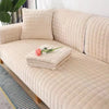 A beige quilted velvet sofa cushion cover on a light wood frame with a striped rug.