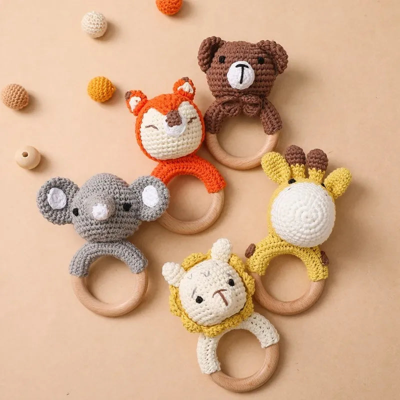 A collection of crochet bunny rattles and teether rings in various colors like brown, orange, gray, and yellow.