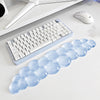 A light blue, cloud-shaped ergonomic wrist rest set for a keyboard and mouse is displayed on a white desk.