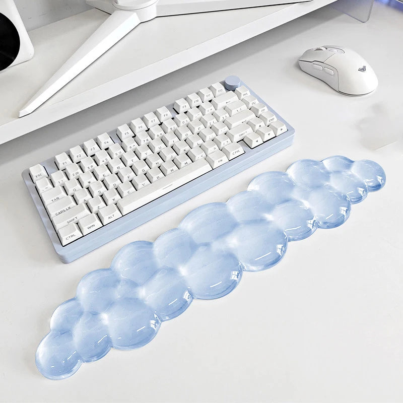 A light blue, cloud-shaped ergonomic wrist rest set for a keyboard and mouse is displayed on a white desk.