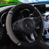 A black steering wheel with a diamond-patterned faux leather cover and accents is visible inside a car interior.