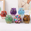 A collection of handcrafted crystal owl figurines in various colors and finishes displayed on a white surface.