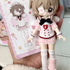 A detailed figurine of a female character dressed in a pink outfit and white uniform, holding a card featuring the same chara