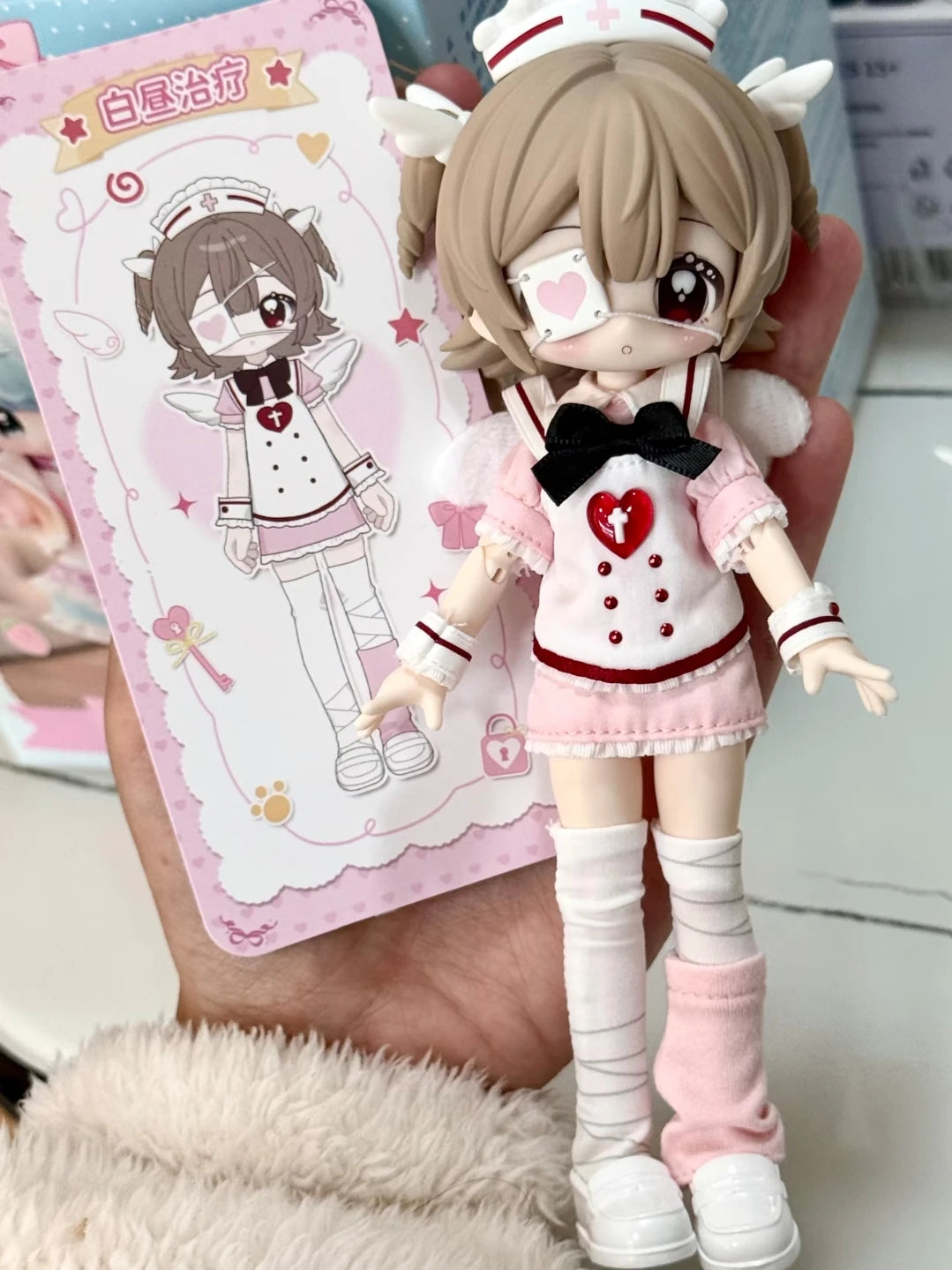 A detailed figurine of a female character dressed in a pink outfit and white uniform, holding a card featuring the same chara